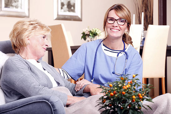 Portrait of happy nurse and senior patient sitting in assisted living community